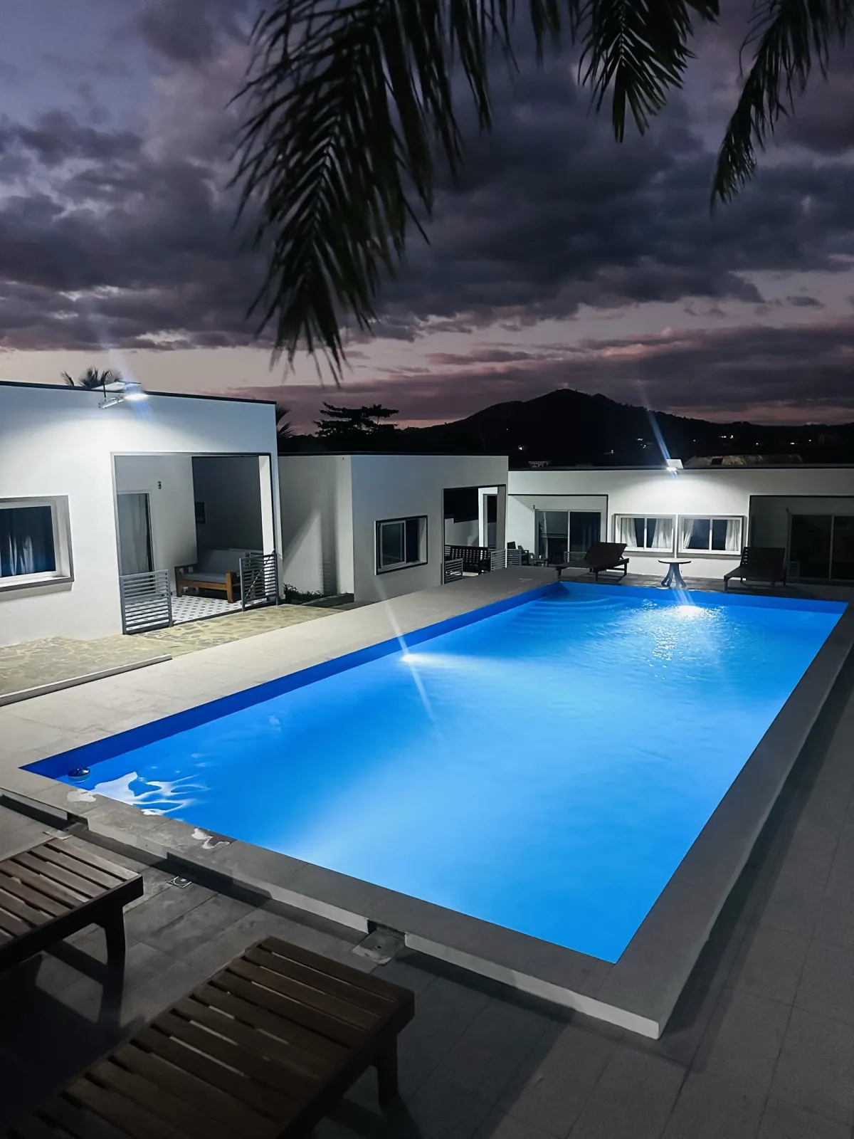 La piscine illuminée au crépuscule, face aux demeures